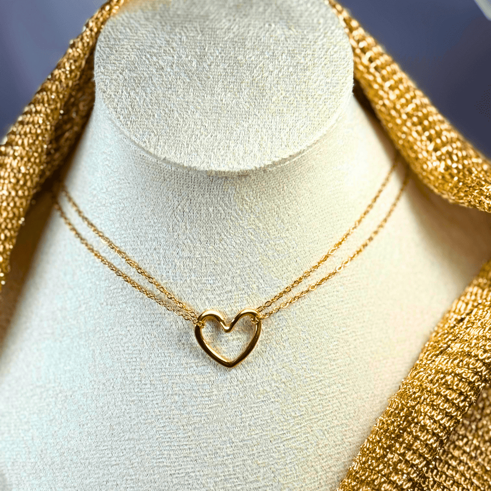 Gold heart-shaped necklace on a mannequin bust with gold fabric background