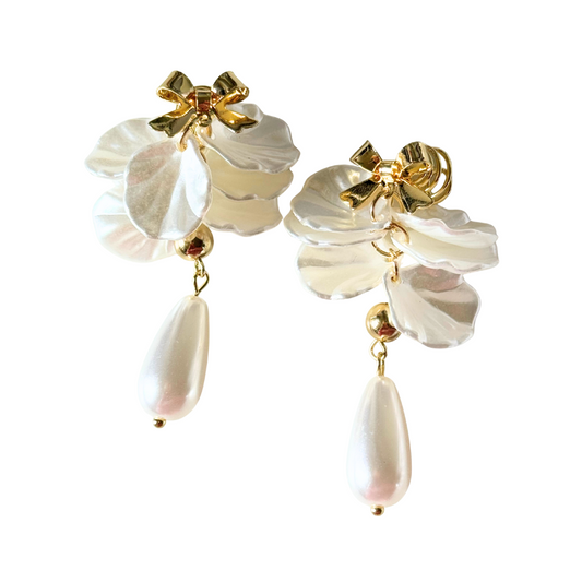 Pair of earrings with gold bows and white floral elements on a white background