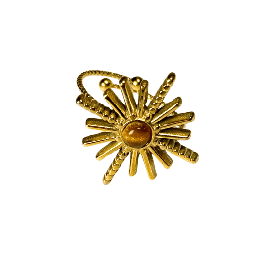 Gold ring with sunburst design and central gemstone on a white background