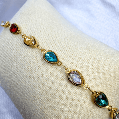 Gold bracelet with multicolored gemstones on a white cushion