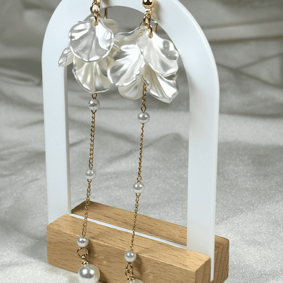 Pearl earrings on a white stand with a wooden base