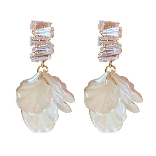 Pair of earrings with shell-like designs and crystal-like top elements on a white background