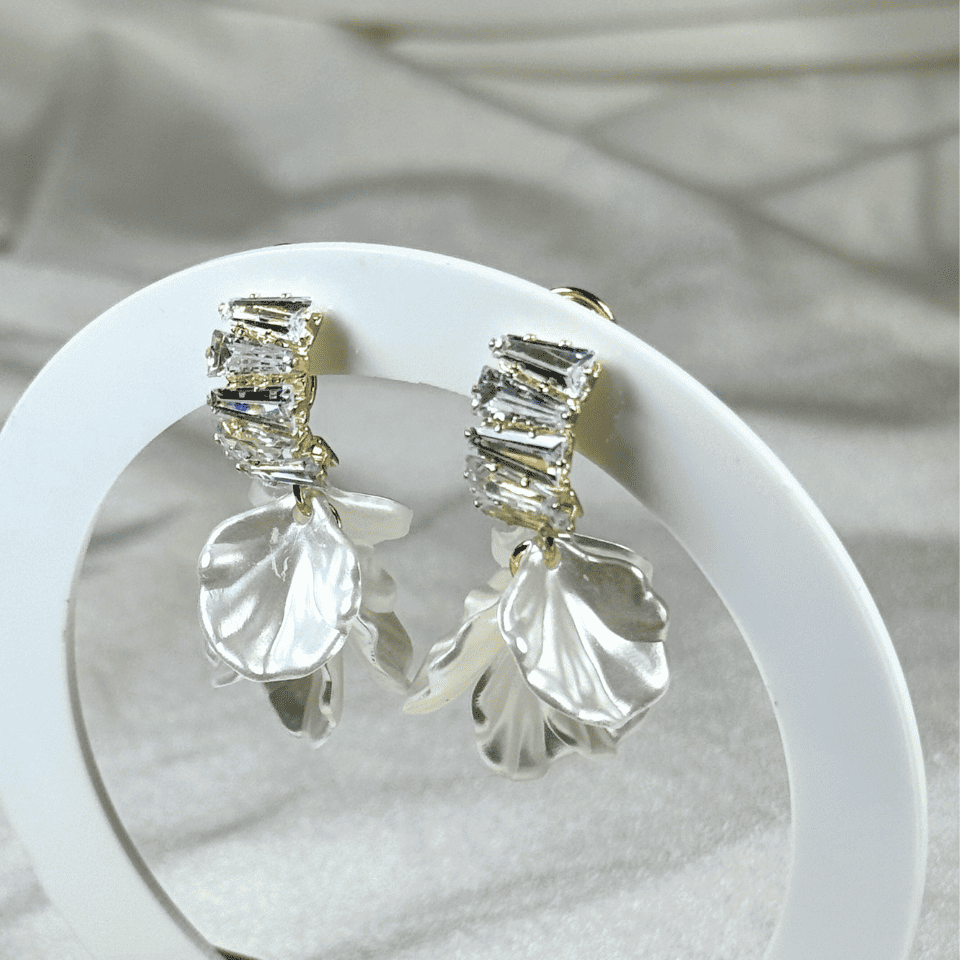 Silver earrings with clear stones on a white plate