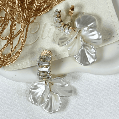 Silver floral earrings with gemstones on a white surface
