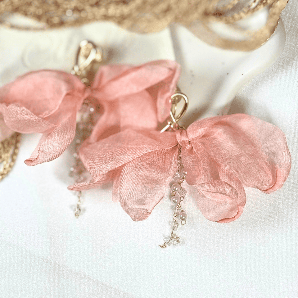 Pink floral earrings with gold accents on a white background