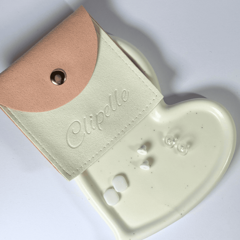 Heart-shaped jewelry dish with a small pouch labeled 'Clipelle' on a light gray background