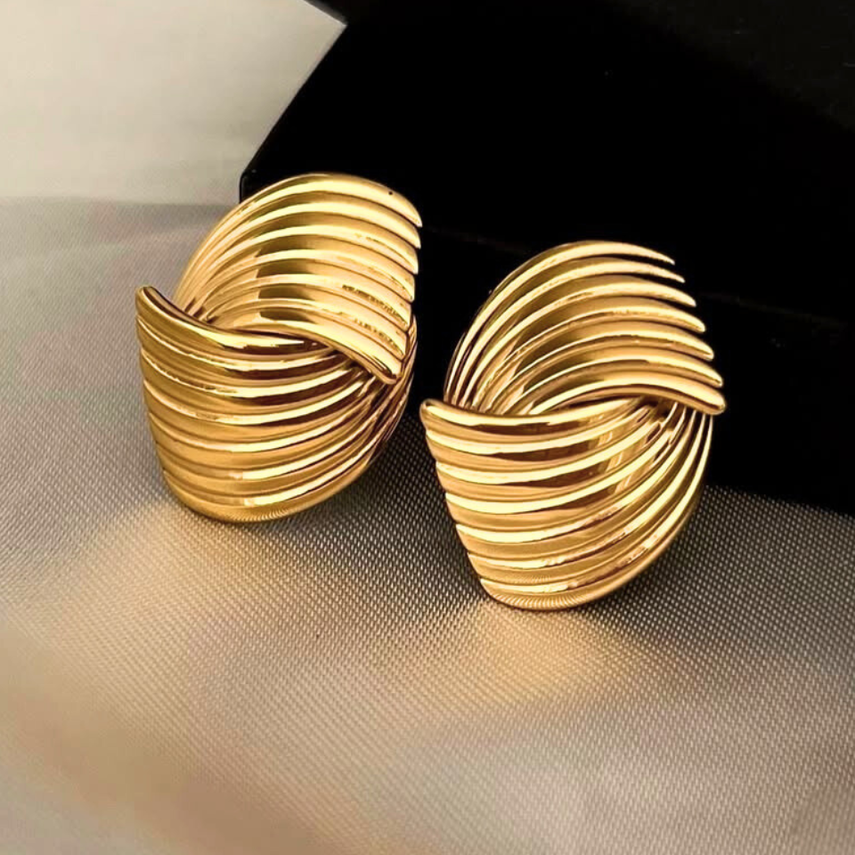Pair of gold earrings on a reflective surface