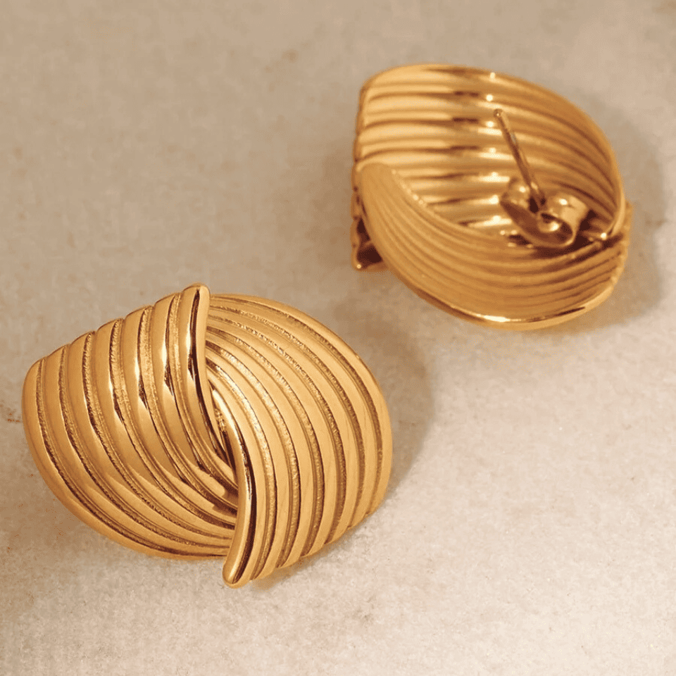 Pair of gold shell-shaped earrings on a beige background