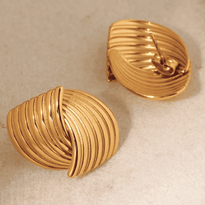 Pair of gold shell-shaped earrings on a beige background