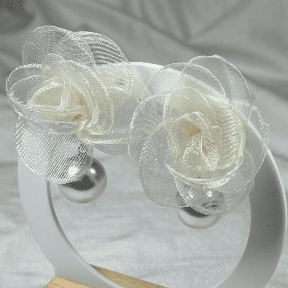 White floral headband on a white stand with a gray fabric background