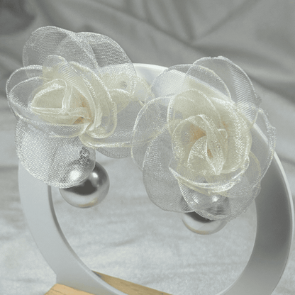 White floral headband on a white stand with a gray fabric background