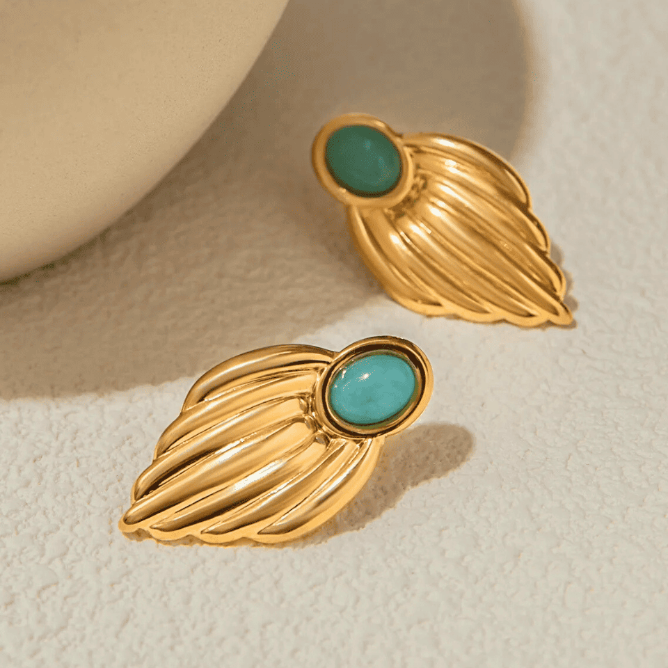 Gold earrings with turquoise stones on a beige background