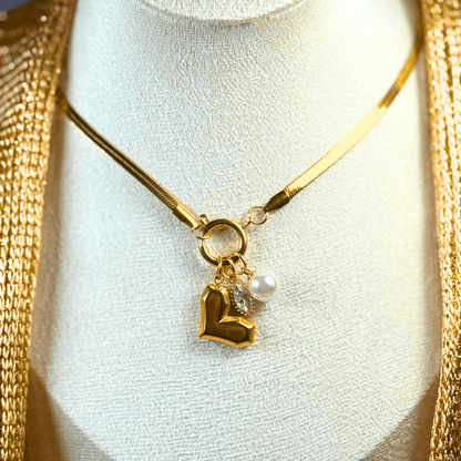 Gold necklace with heart and pearl pendant on a mannequin bust.