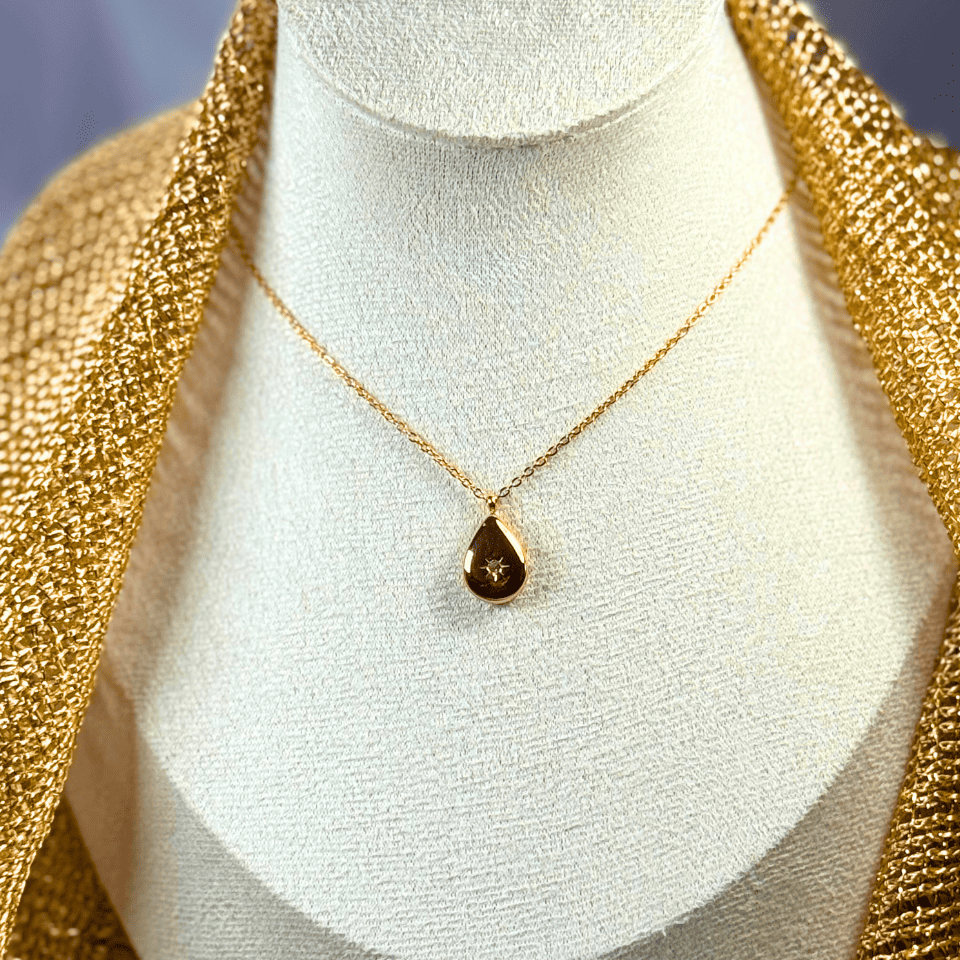 Gold necklace with a teardrop pendant on a mannequin bust.