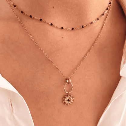 Rose gold necklace with a pendant on a person wearing a white shirt.