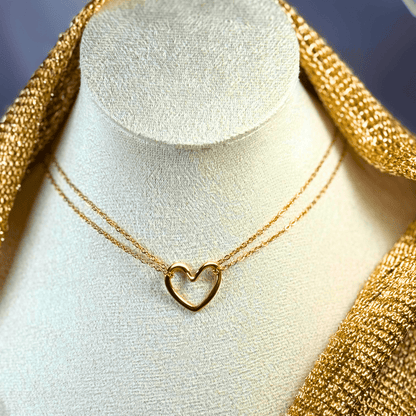 Gold heart-shaped necklace on a mannequin bust with gold fabric background