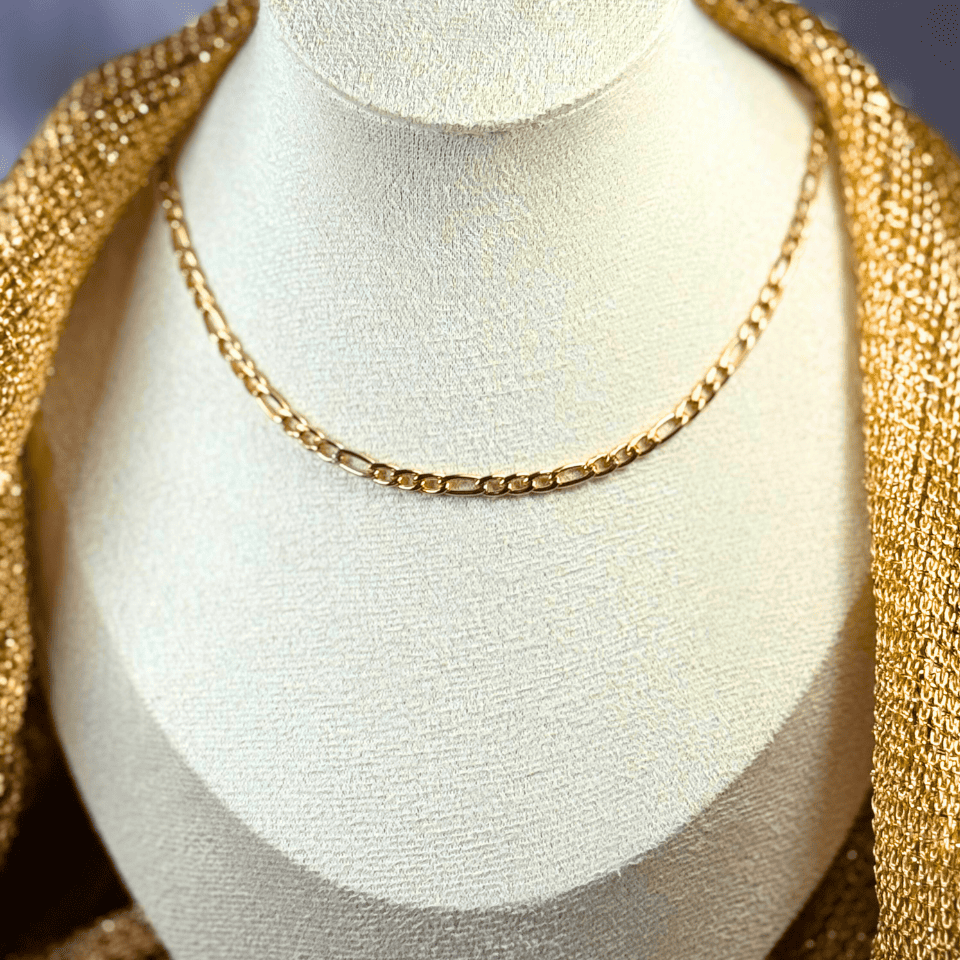 Gold chain necklace on a mannequin bust with a gold garment.