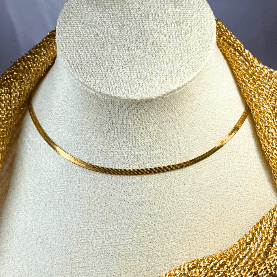 Gold necklace on a white mannequin bust with a gold decorative background