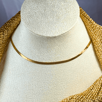 Gold necklace on a white mannequin bust with a gold decorative background