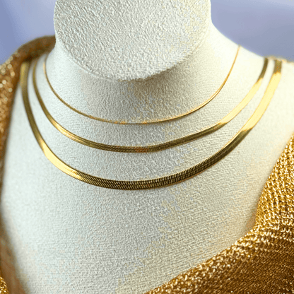Gold necklaces on a mannequin bust with a neutral background