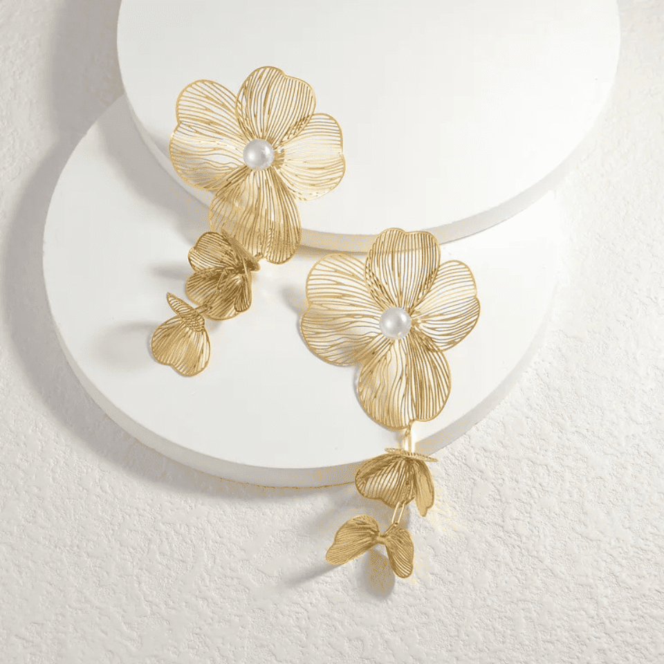 Gold floral earrings with pearl centers on a white background