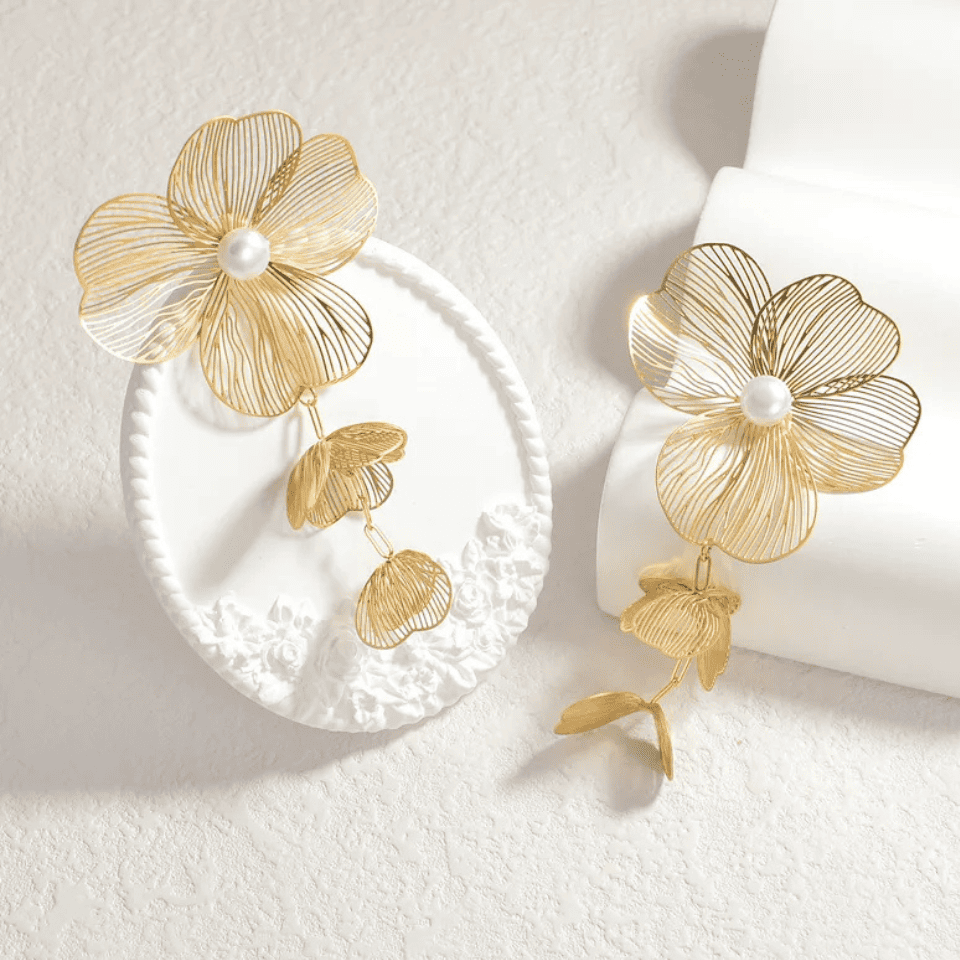Gold floral earrings on a white surface
