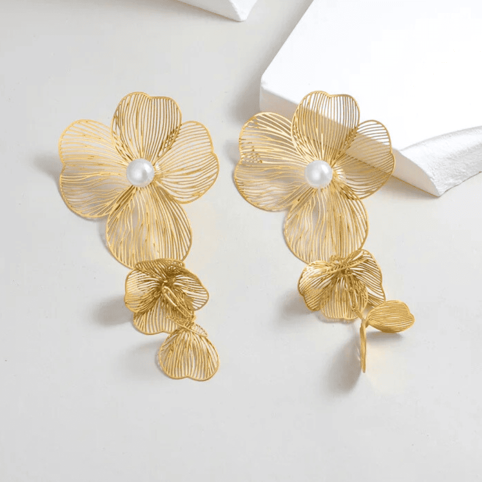 Gold floral earrings with pearl centers on a white background