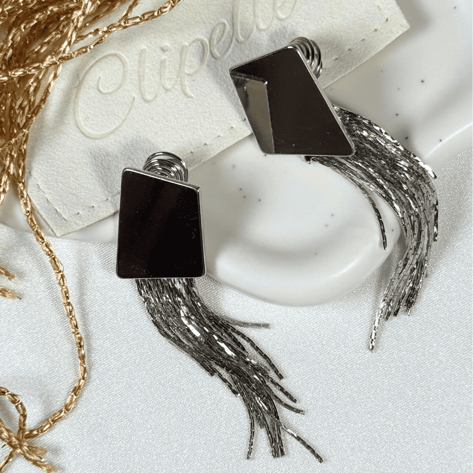 Black square earrings with tassels on a white surface with 'Elipette' branding.