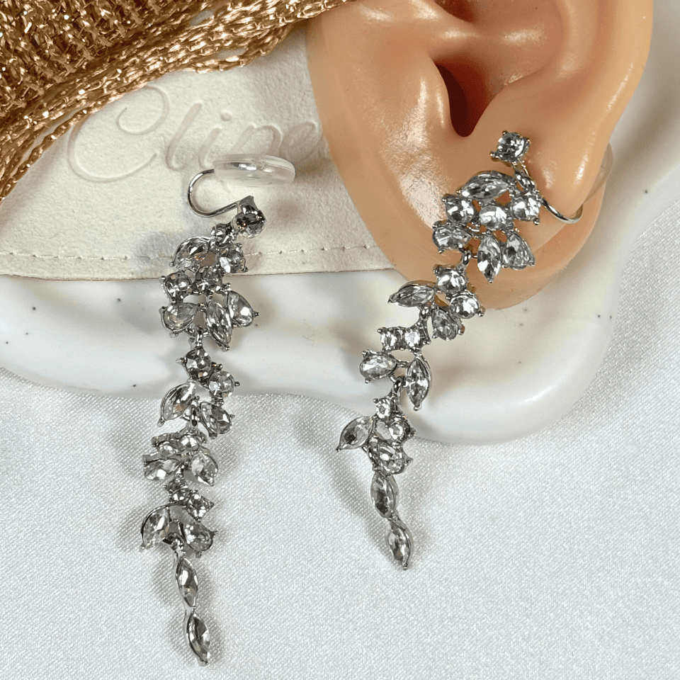 Silver leaf-shaped earrings on a mannequin ear with a white background
