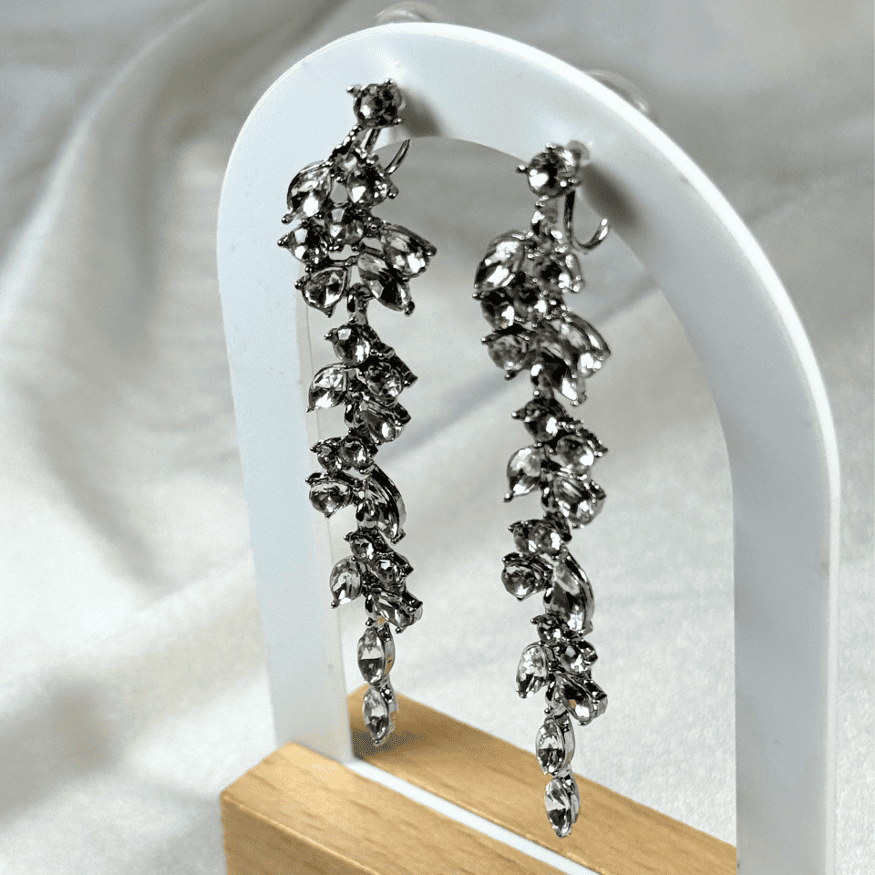 Silver floral earrings on a white stand with a white background