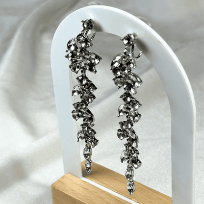 Silver floral earrings on a white stand with a white background