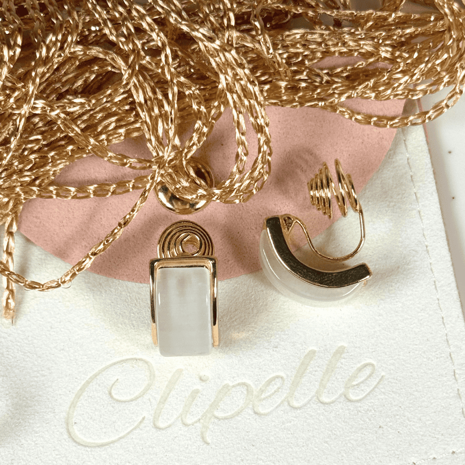 Gold necklace and earrings on a white surface with 'Clipette' branding.