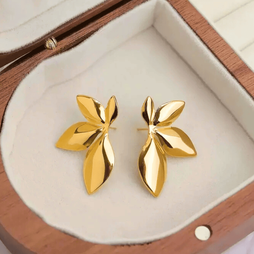 Gold leaf-shaped earrings in a wooden jewelry box