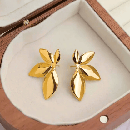 Gold leaf-shaped earrings in a wooden jewelry box