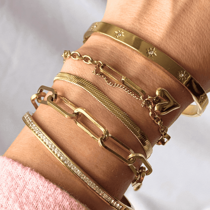 Gold bracelets on a wrist with a plain background