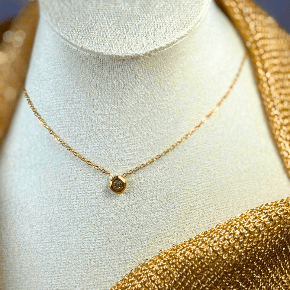 Gold ring with diamonds on a beige jewelry box with gold chains in the background