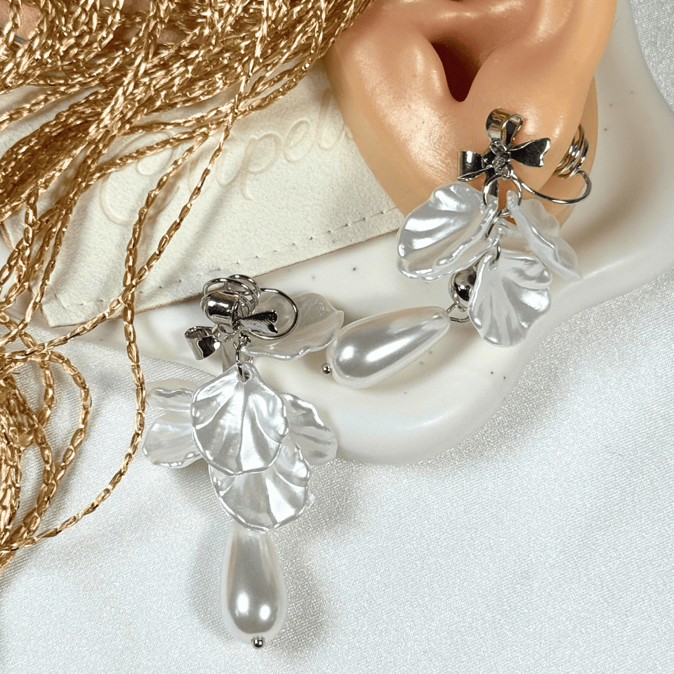 Pearl earrings being worn on an ear with a white background
