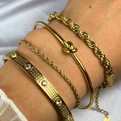 Gold bracelets on a wrist against a white background