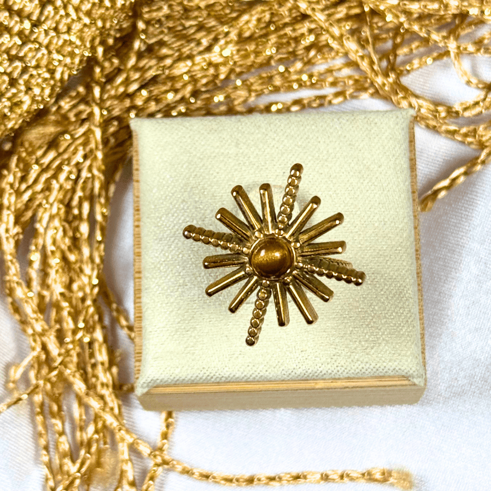 Gold jewelry box with sunburst design on a white background
