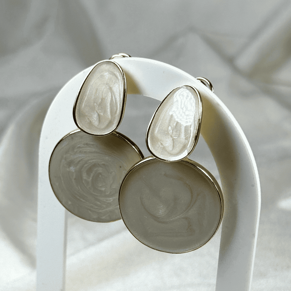 Pair of earrings on a white stand with a soft background