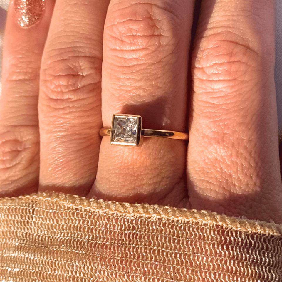 Gold ring with a diamond on a person's finger