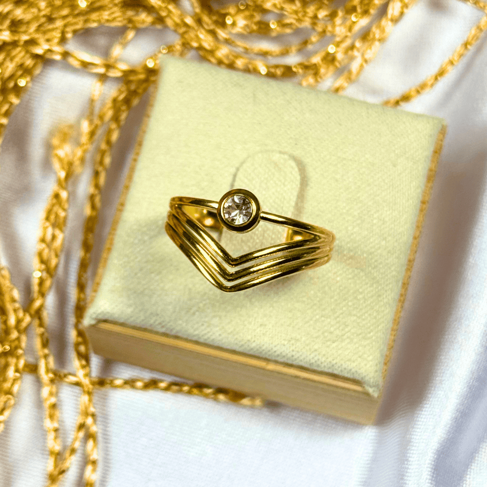 Gold ring with a diamond on a yellow jewelry box with gold chain
