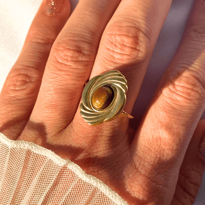 Gold ring with a brown gemstone on a hand