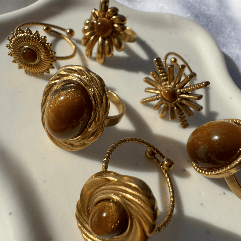 Gold rings with brown gemstones on a white surface